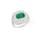 AN EARLY 20TH CENTURY EMERALD AND DIAMOND DRESS RING The rectangular cut-cornered emerald within