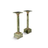 A PAIR OF GREEN ONYX COLUMNS, with square tops above cast brass capitals, on square pedestal