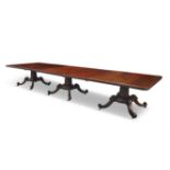 A GEORGE III MAHOGANY THREE-PILLAR EXTENDING DINING TABLE, the top with reeded rim, raised on