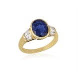 AN 18CT GOLD, SAPPHIRE AND DIAMOND RING The oval, mixed-cut sapphire flanked on each side by