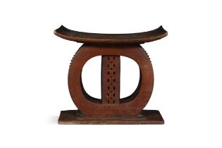 AN AFRICAN HARDWOOD STOOL, Ashanti, Ghana, with bowed seat supported on a lattice work centre