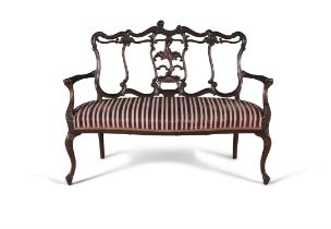 A LATE VICTORIAN CARVED MAHOGANY FRAMED SETTEE, with carved openwork back, upholstered in a