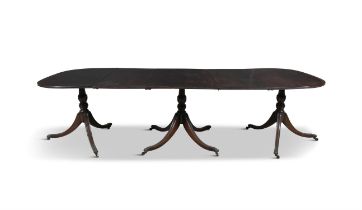 A GEORGE III STYLE MAHOGANY TRIPLE PEDESTAL DINING TABLE with reeded rim, the pods on central