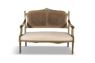 A FRENCH GILTWOOD AND CANEWORK BERGERE SETTEE the carved top rail centred with a ribbon tied