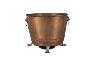 AN OVAL COPPER FUEL BUCKET with brass lion mask ring handles, on cast paw feet. 50cm diameter,