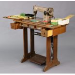 A Singer electric treadle sewing machine in an oak case, 34” wide.