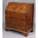 A Georgian mahogany small bureau with a fitted interior enclose by a fall-front above four long