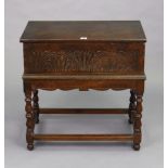 An antique carved oak bible-box with a hinged lift-lid, & on a table stand having baluster-turned