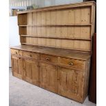 A Victorian pine dresser, the upper part fitted three open shelves & with a panelled back, the