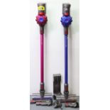 Two Dyson stick vacuum cleaners with various accessories.
