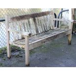 A teak wooden slatted garden bench on square legs, 60” long.