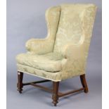 A Late 19th/early 20th century wing-back armchair (requires re-upholstery), on short square fluted