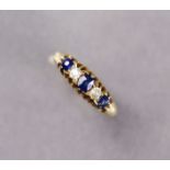 A late Victorian 18ct gold ring set three sapphires intersected by two small diamonds, size L. (3.