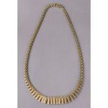 A 9ct three-colour gold flexible brick-link necklace with graduated baton pendants, 18” long. (23.