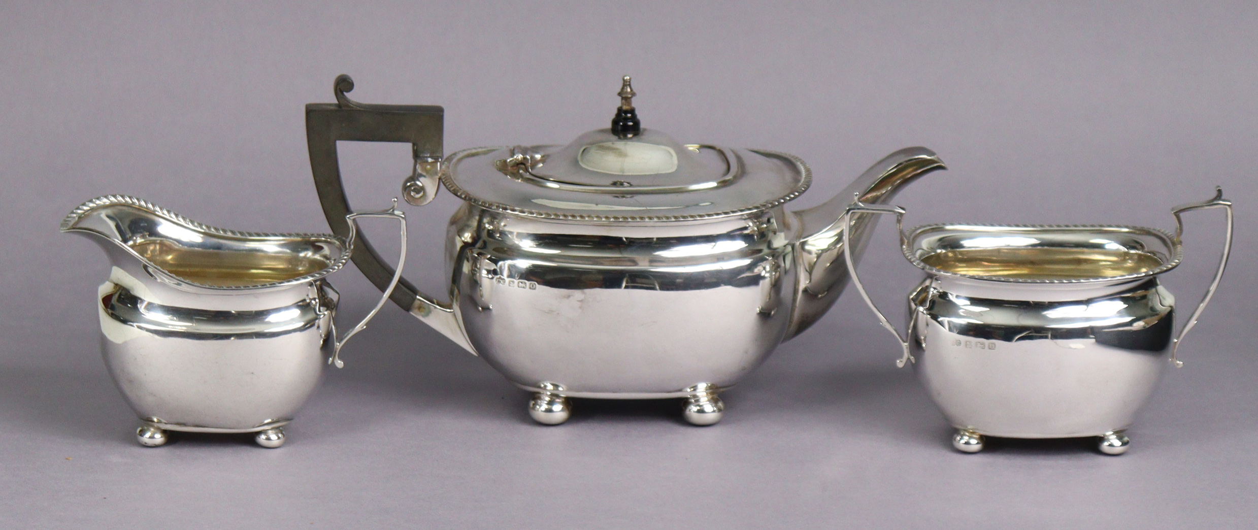 A George VI silver three-piece tea service in the regency style, of compressed oblong form with