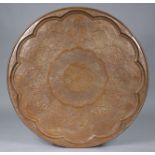 An eastern embossed copper circular table-top or tray, decorated with foliate scrolls & reserves