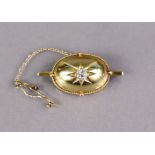 A 15ct gold dome-shaped oval brooch set cushion-shaped diamond to the centre, within a narrow rope-