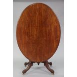 A Victorian mahogany loo table with moulded edge to the oval tilt-top, on vase-turned centre