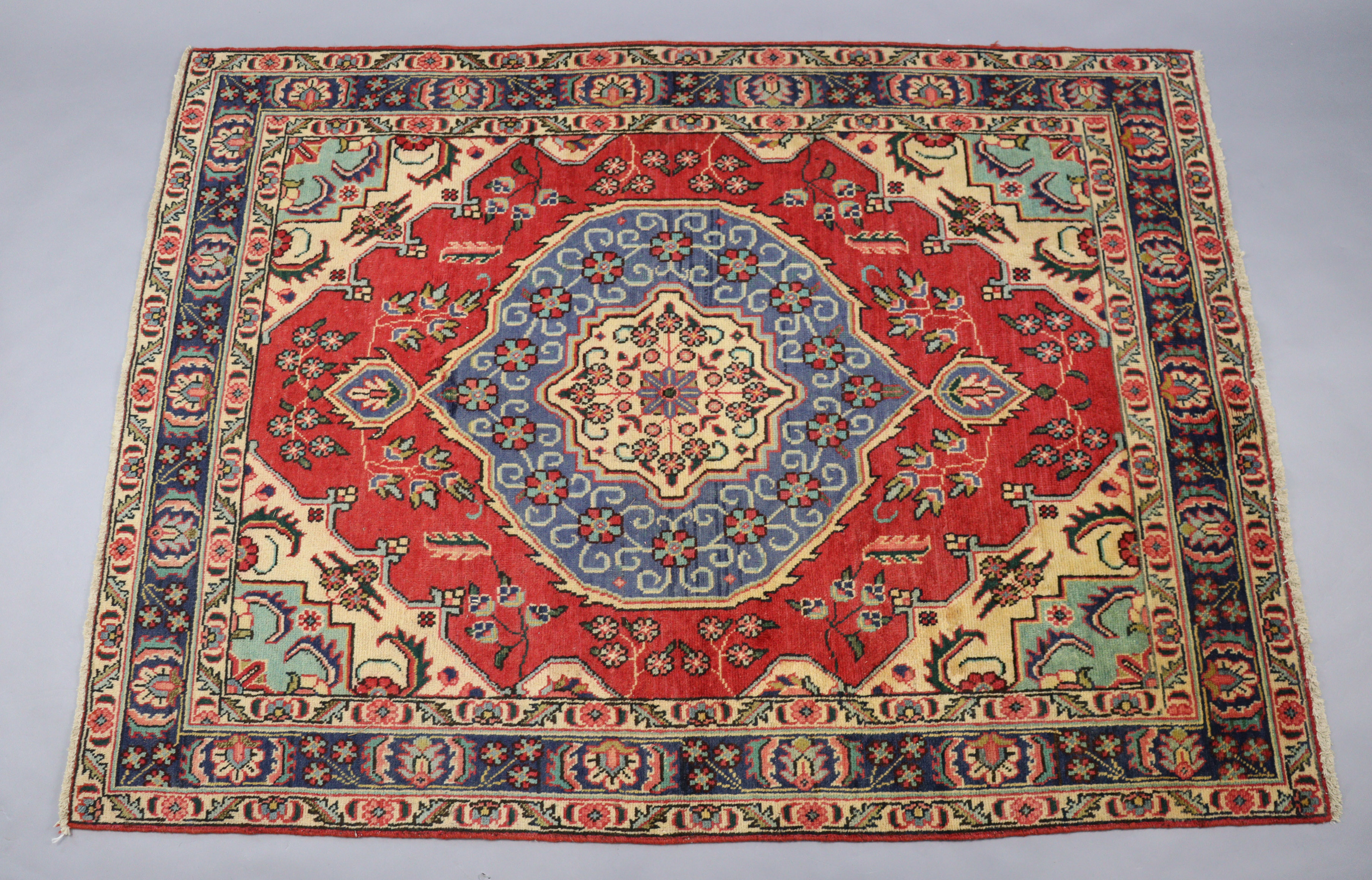 A north west Persian Tabriz rug of madder ground, the central medallion surrounded by floral motifs,