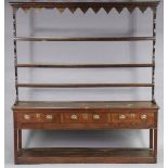 AN 18th century OAK DRESSER, with moulded cornice above three open shelves, fitted three frieze