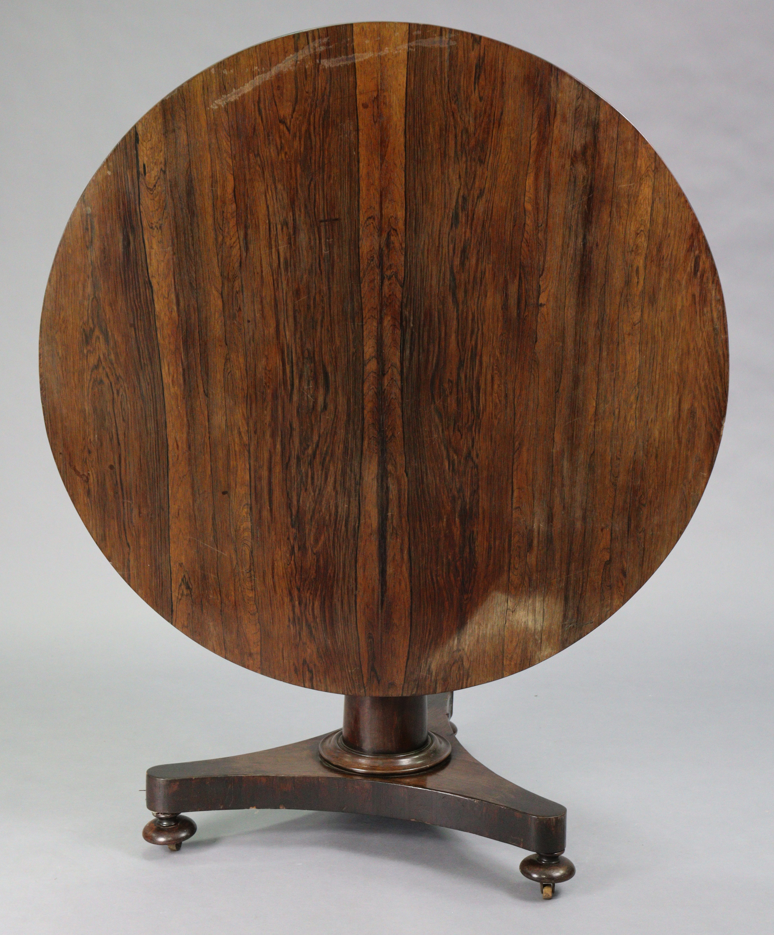 An early Victorian rosewood loo table with circular tilt-top, on tapered centre column & triform