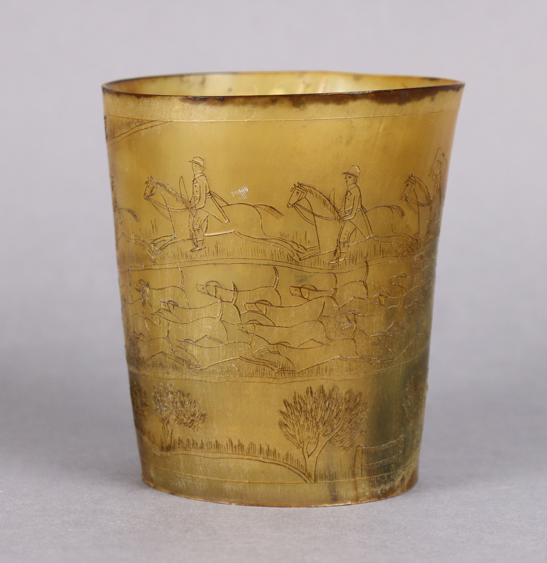 A 19th century horn beaker, all over engraved with a busy hunting scene, 4½” high x 4” dia.