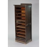 A mid-20th century oak upright office cabinet fitted nine sliding trays enclosed by a tambour