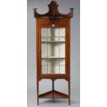 An Edwardian inlaid-mahogany standing corner cabinet fitted two shelves enclosed by a leaded