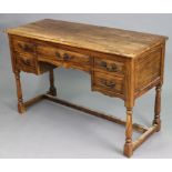 A teak knee-hole dressing table fitted with an arrangement of five drawers, & on baluster-turned