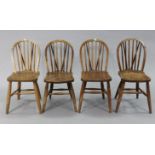 A set of four spindle-back kitchen chairs with hard seats, & on turned legs with spindle stretchers.