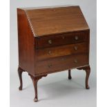 An Edwardian mahogany small bureau with a fitted interior enclosed by a fall-front above three