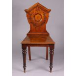 A Victorian mahogany hall chair with a carved panel back, hard seat, & on turned and fluted