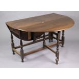 A 1930’s oak oval gate-leg dining table fitted end drawer, & on baluster-turned legs & turned feet