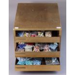 A wooden three-drawer counter-top chest, 12¾” wide x 9½” high, containing various assorted beads.