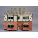 A mid-20th century painted & paper-covered wooden cottage-style two-storey doll’s house with an