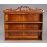 A set of Victorian mahogany wall-mounted book-shelves with a pierced & carved pediment, & with two