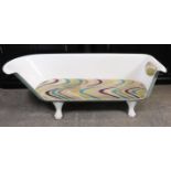 A white enamelled cast-iron novelty low window seat in the form of a bath-tub with a padded