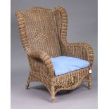 A rattan wing-back armchair with loose cushion to seat.