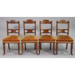 A set of four early 20th century carved walnut rail-back dining chairs with padded seats, & on