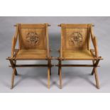 A pair of early 20th century oak Glastonbury-type elbow chairs with carved floral roundels to the