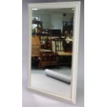 A large rectangular wall mirror in a light grey painted wooden frame, & inset with a bevelled plate,