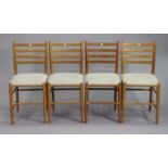 A set of four teak ladder-back dining chairs with padded seats, & on round tapered legs with spindle