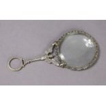 A continental silver magnifying glass with decorative border, & winged cariatide forming the handle,