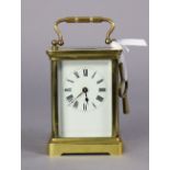 A late 19th century brass carriage clock, the white enamel dial with Roman numerals, the movement