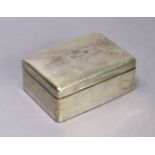 A George V silver rectangular cigarette box with engraved family crest to the hinged lid, rounded