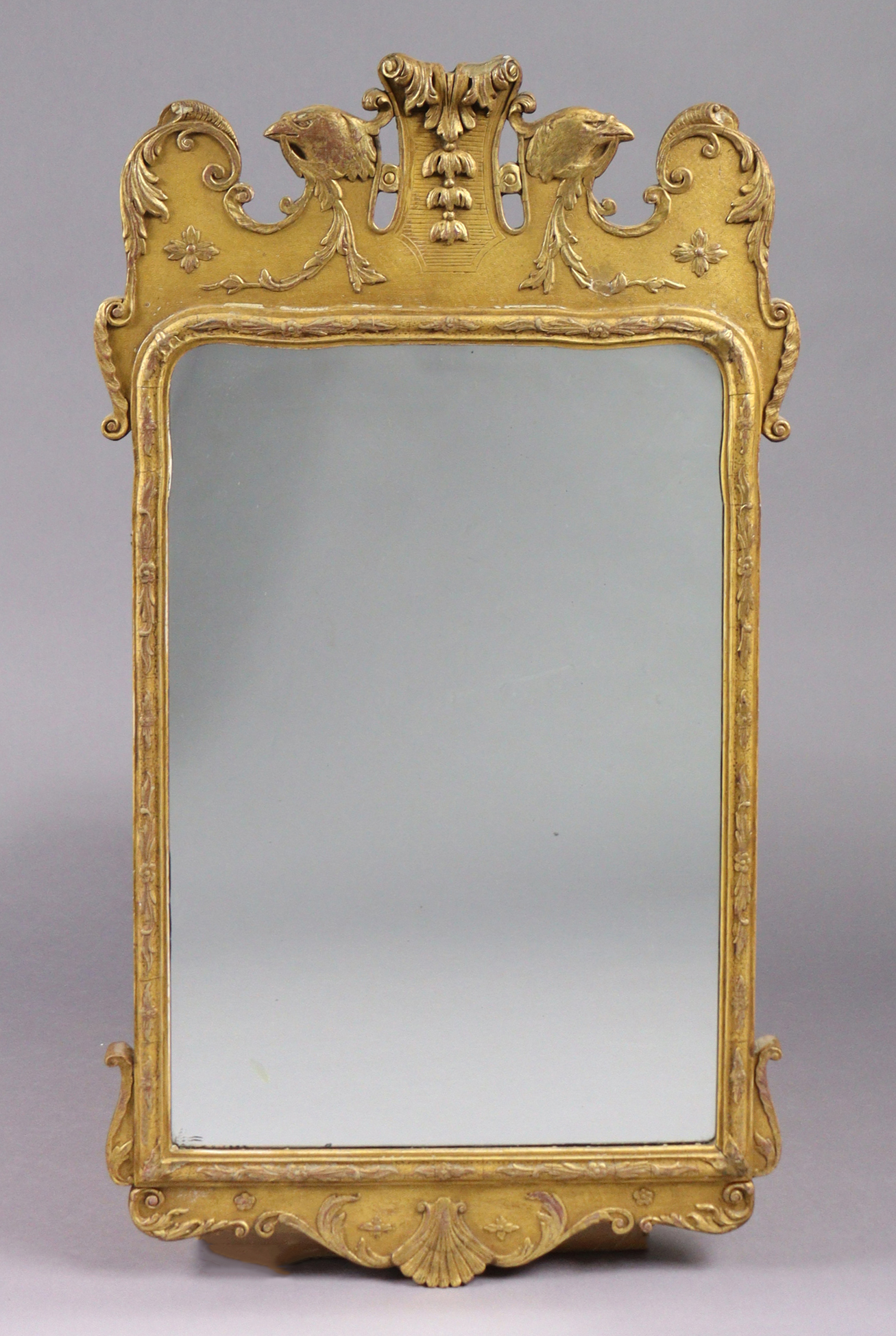 A George I style carved giltwood & gesso wall mirror, of shaped rectangular form with foliate