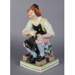 A 19th century Staffordshire pottery figure of a cobbler, with painted & gilt decoration, on