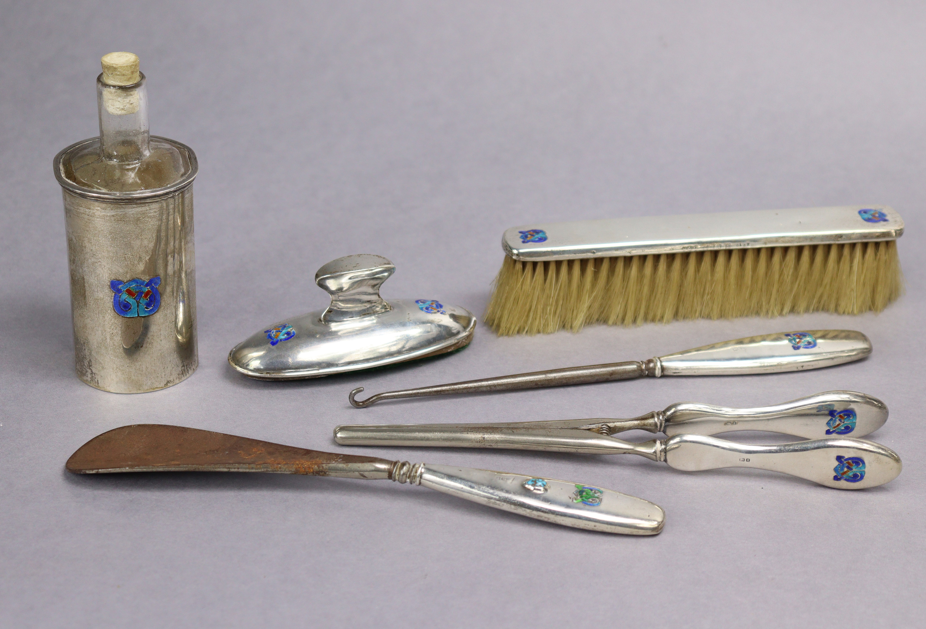 A Liberty & Co. “Cymric” silver part dressing table set with coloured enamel Celtic motifs,