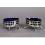 A pair of George III silver oval salt cellars with pierced, decorated sides & blue glass liners,