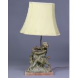 A 19th century style cast metal table lamp in the form of a putto taming a ram, on rouge alabaster